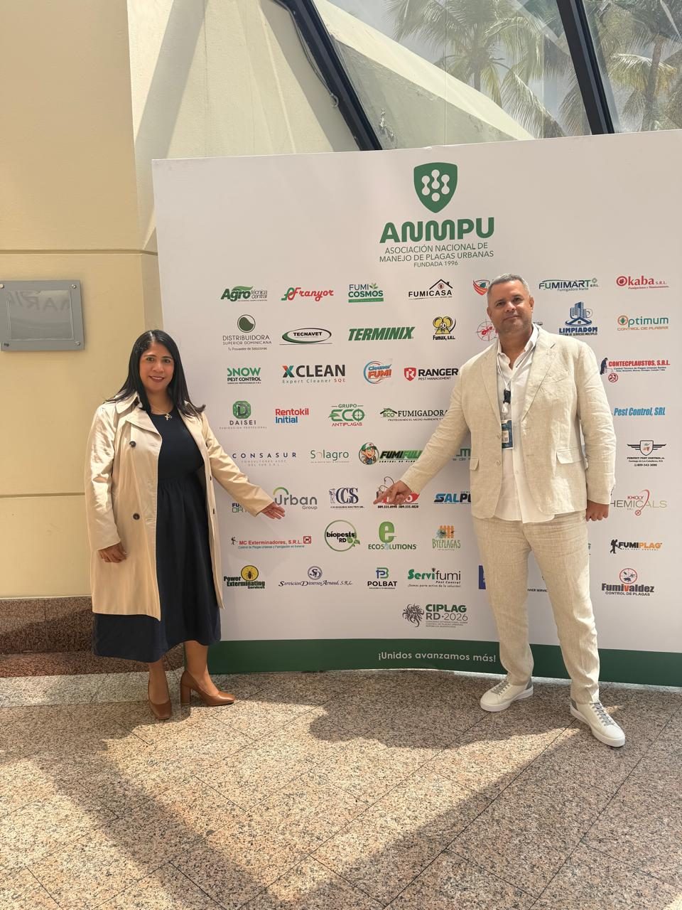 Equipo de BioPests RD frente al mural de empresas miembro de ANMPU